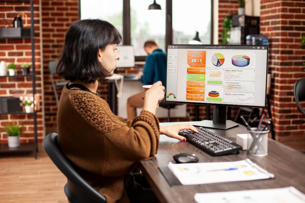 A woman reviews business charts on a computer.